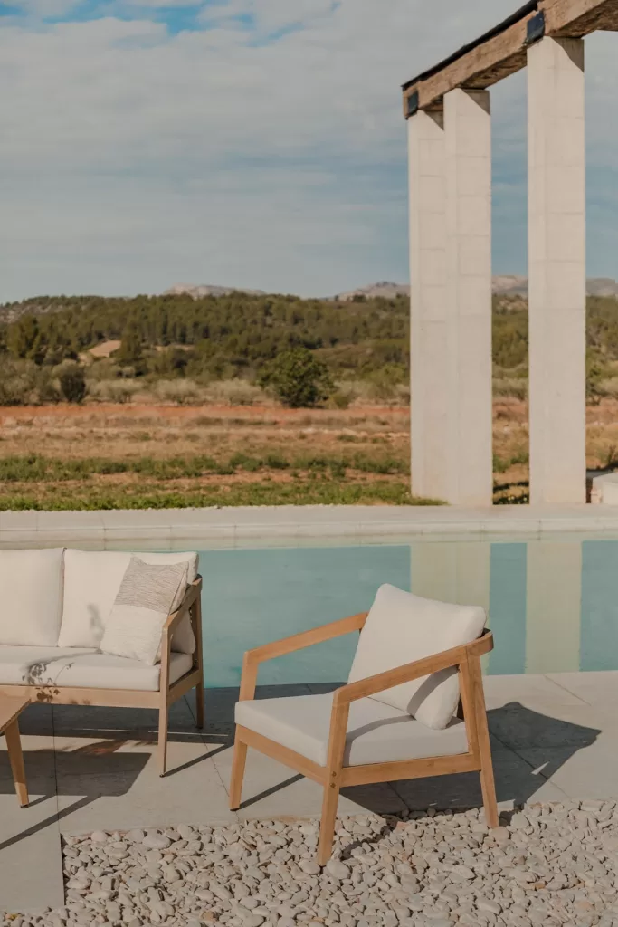 Sillón de jardín de madera de acacia colocado junto a una piscina en un entorno natural, perfecto para decorar áreas exteriores.