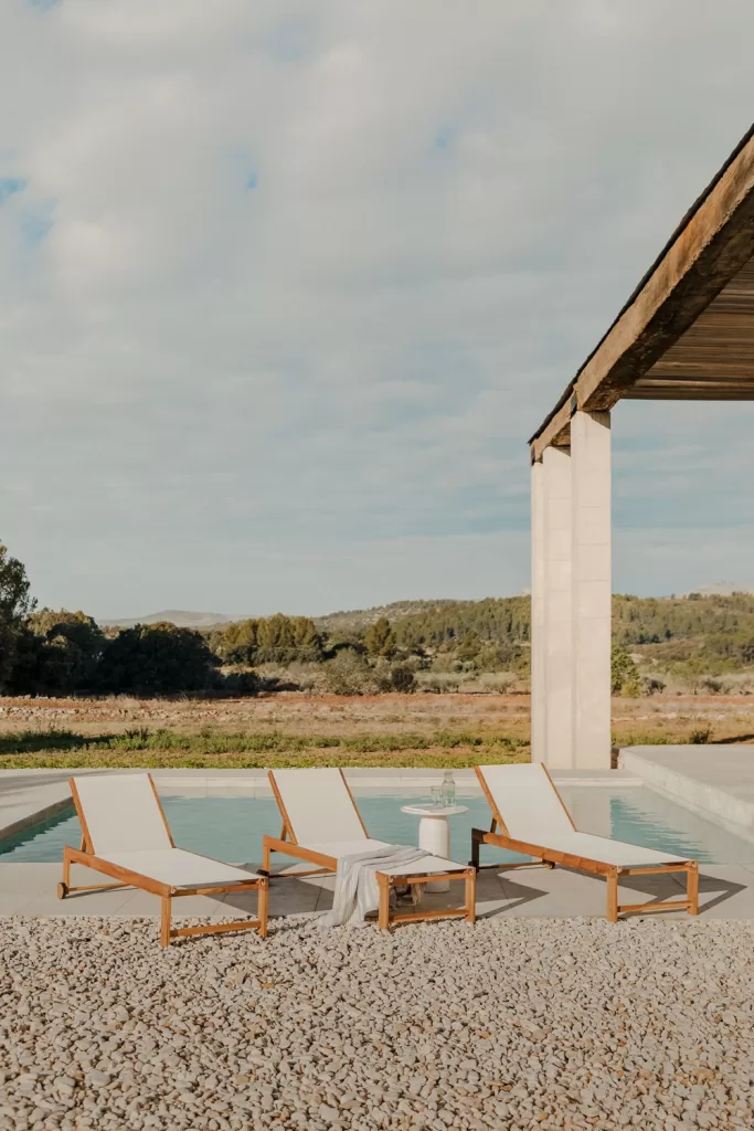 Tres tumbonas reclinables de madera colocadas junto a una piscina, perfectas para decorar un jardín con piscina y disfrutar del verano.