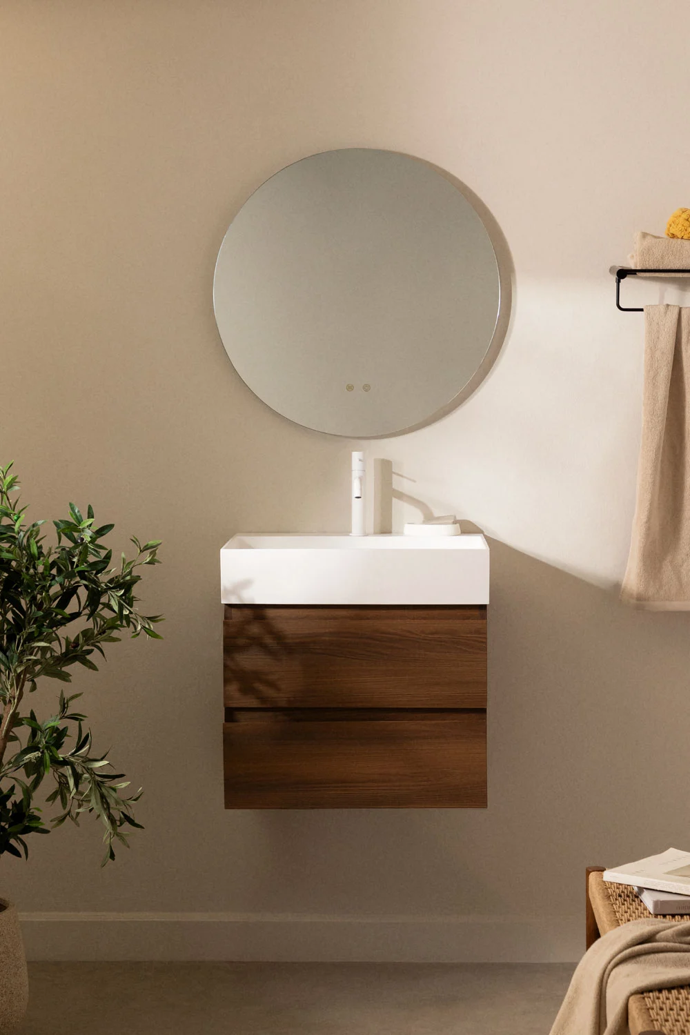 Piccolo bagno con mobili sospesi in legno scuro e specchio rotondo. Un design equilibrato che evita la saturazione visiva e massimizza lo spazio.